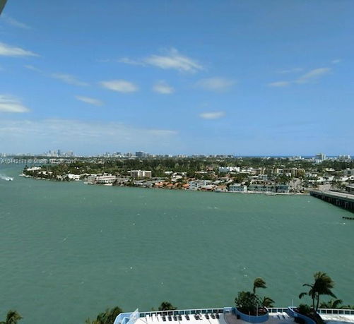 View of a coastal area with buildings and water, seen from a higher vantage point.