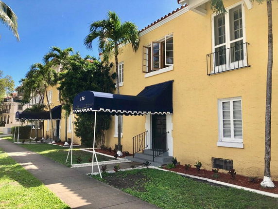Front view of a two-story yellow building with blue awnings.