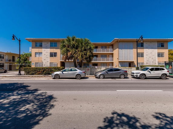 Front view of a three-story apartment building with a flat roof and balconies.
