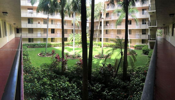 Exterior view of a multi-story residential building with balconies facing a central courtyard.