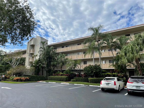 Front view of a multi-story residential building with an outdoor parking area.