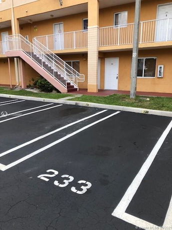 Outdoor parking area in front of a building with numbered parking spots.