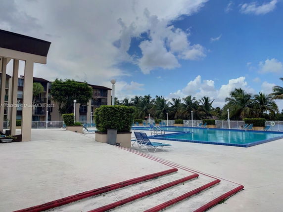 Outdoor swimming pool area with lounge chairs and surrounding buildings.