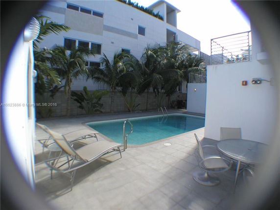 Outdoor swimming pool area with lounge chairs and table.