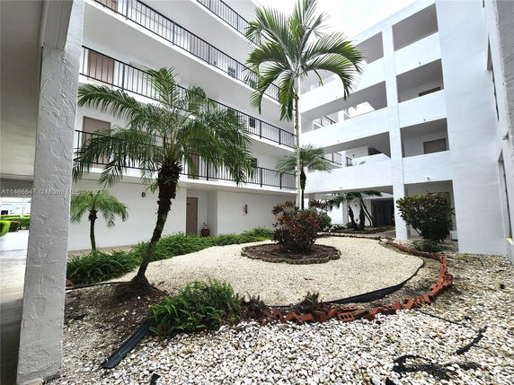 Exterior view of a multi-story building with balconies and landscaped courtyard.