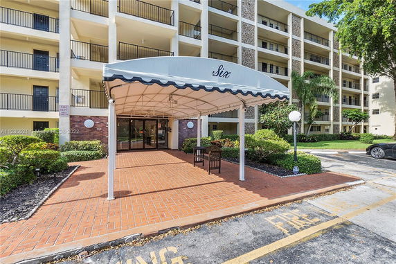 Front view of a multi-story residential building with balconies and a covered entrance.