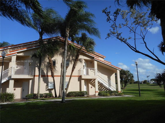 Front view of a two-story building with exterior staircases and a sloped roof.