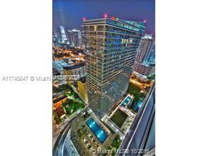 Panoramic view of a multi-story building surrounded by cityscape at night.