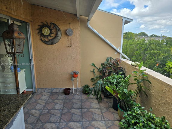 Outdoor balcony area with plants and decorative wall art.