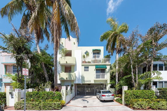 Front view of a multi-story building with balconies and a parking area.