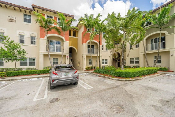 Front view of a multi-story building with balconies and palm trees.