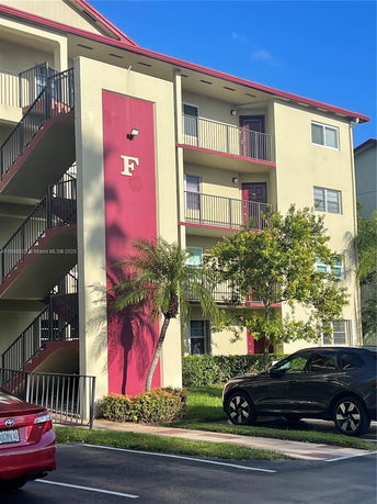 Front view of a multi-story apartment building with external staircases and marked building section 'F'.