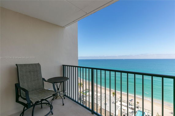 Balcony view overlooking a vast ocean and beach.