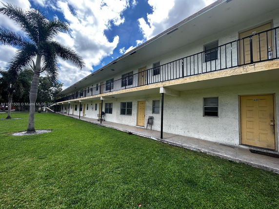 Front view of a two-story residential building with multiple doors and a walkway.