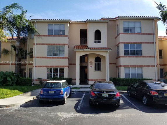 Front view of a three-story apartment building with parking area.