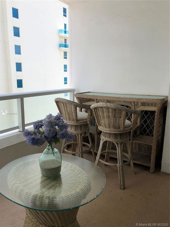 View of a balcony with wicker furniture facing nearby building.