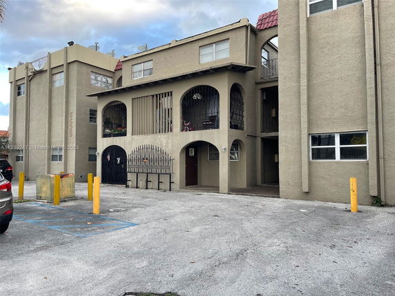Front view of a multi-story building with an entrance and parking spaces.