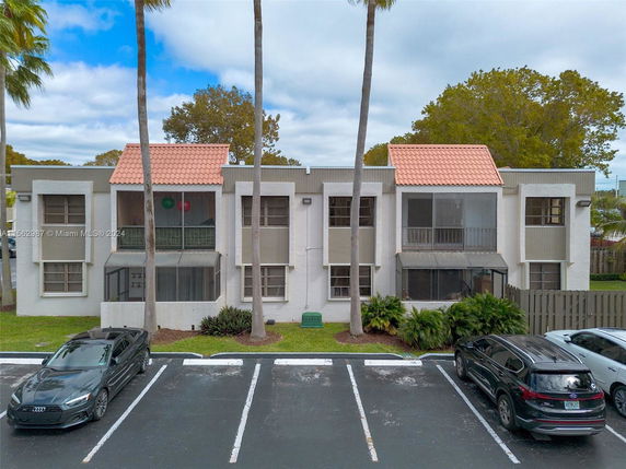 Front view of a two-story building with screened balconies and multiple windows.