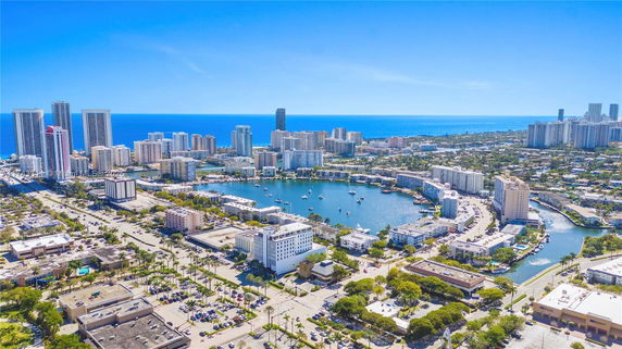 Wide aerial view of a coastal cityscape with high-rise buildings and waterfront area.