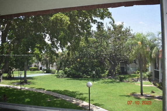 View of surrounding area with green lawns and trees, and a glimpse of a building in the background.