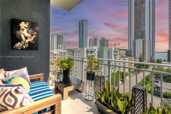 View of surrounding buildings from a balcony with plants and seating.