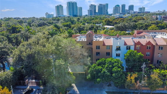 Aerial view of a residential building with treetops and high-rise buildings in the background.