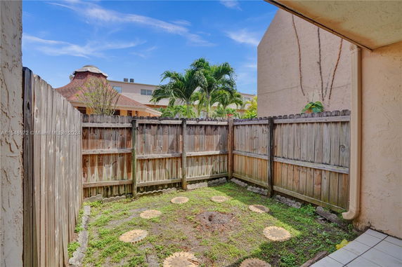 Outdoor area with wooden fence and view of neighboring buildings and trees.