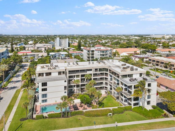 Aerial view of a multi-story apartment complex with balconies and a swimming pool.