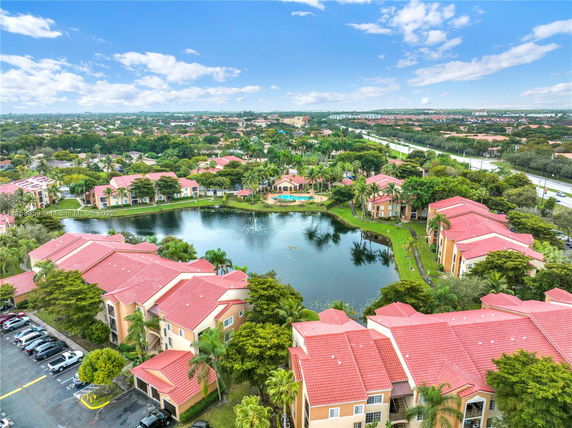 Panoramic view of apartment buildings around a lake with red tile roofs.