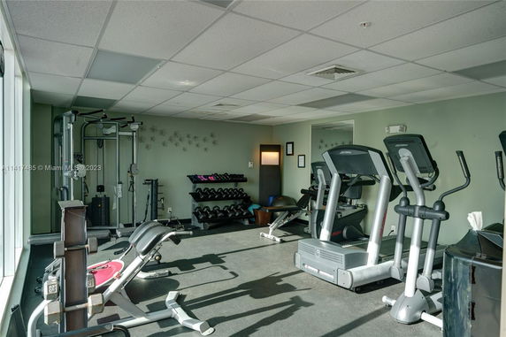 Gym area with exercise equipment including treadmills and weights.