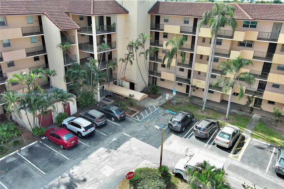 Exterior view of a multi-story residential building with a parking area in front.
