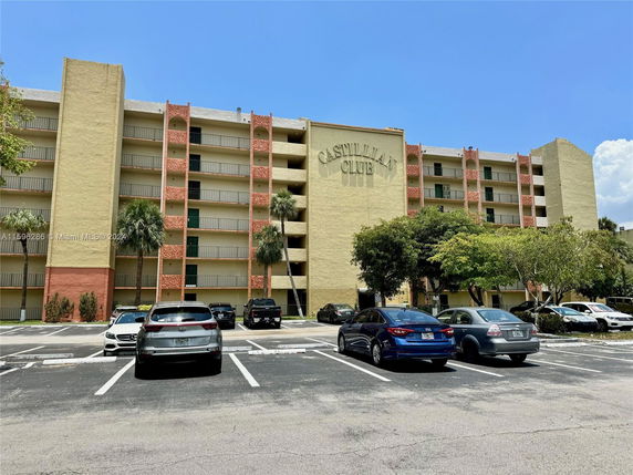 Front view of a multi-story residential building with a parking area in front.