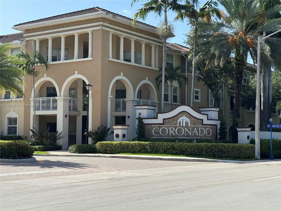 Front view of a multi-story building with arched windows and a sign reading 'Coronado'.