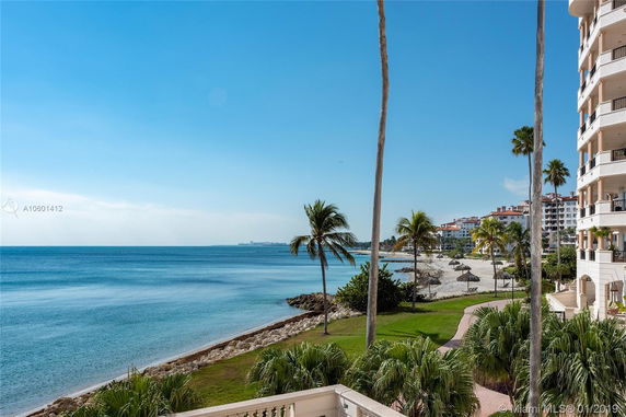 View of a beachfront area with palm trees and nearby buildings.