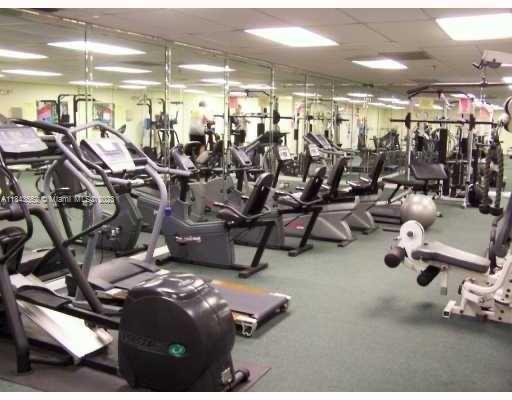 Indoor club house gym area with various exercise equipment and mirrored walls.