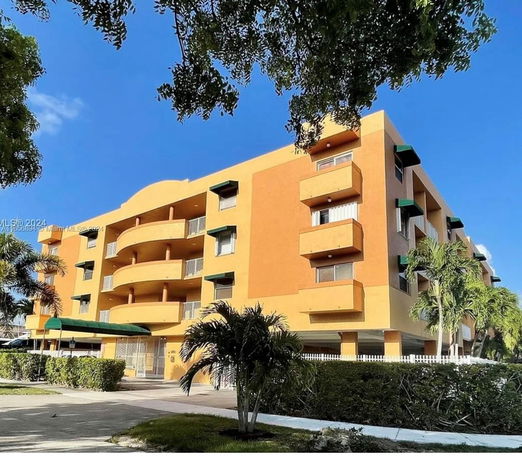 Front view of a four-story apartment building with balconies and a yellow facade.