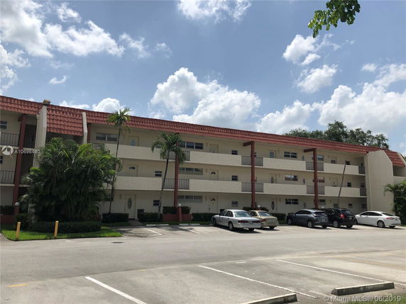 Front view of a multi-story residential building with a tiled roof and balconies.