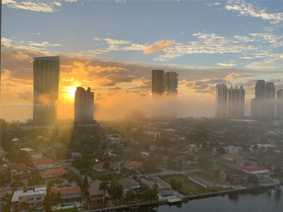 Panoramic view of a cityscape with high-rise buildings and a sunset.