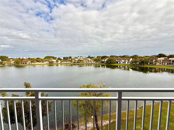 Panoramic view of a peaceful lake with houses in the background, seen from a balcony.