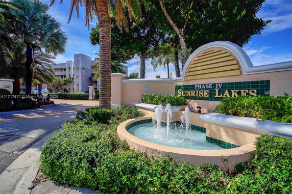 Front view of a residential complex with a decorative fountain and greenery.