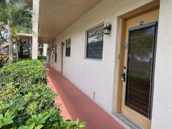 Exterior view of an apartment building corridor with doors and windows.