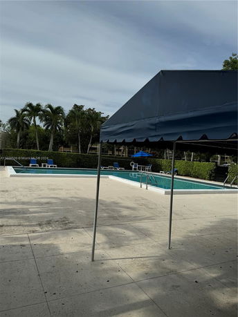 Outdoor swimming pool area with lounge chairs and a shaded canopy.