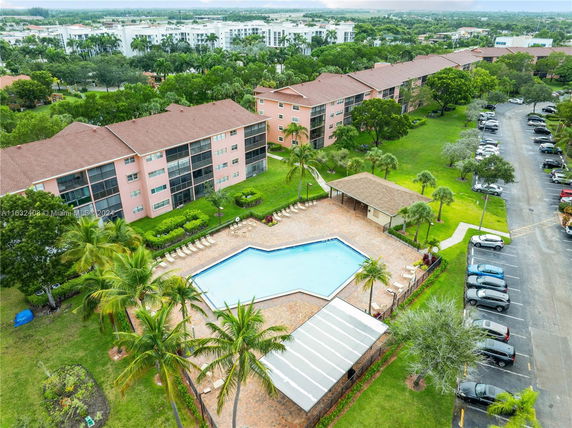 Aerial view of a residential area with a swimming pool and multi-story apartment buildings.