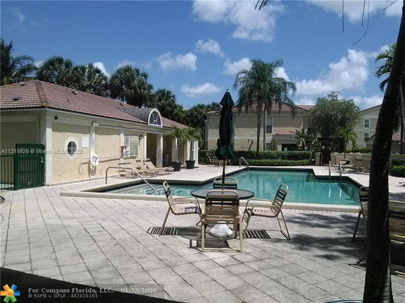 Outdoor swimming pool area with surrounding chairs and tables.