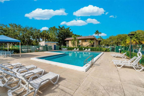 Outdoor swimming pool with lounge chairs and a small building nearby.