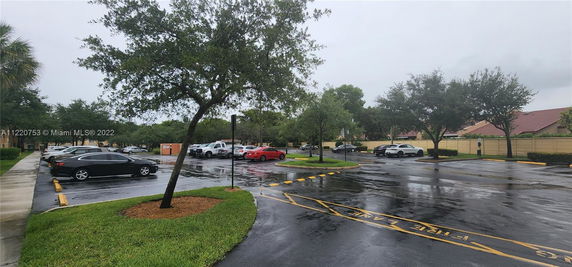 Outdoor parking area with several parked cars and surrounding trees.