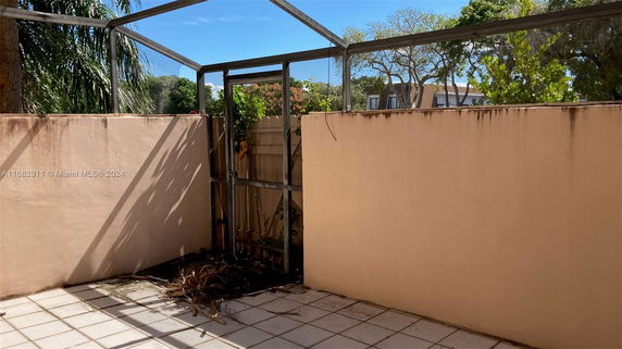 Outdoor patio area with tiled flooring and tall surrounding walls.