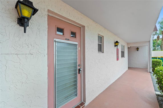 Front view of a building entrance with a pink door and exterior wall lamps.