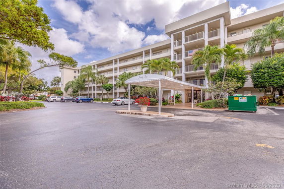 Front view of a multi-story residential building with balconies and entrance canopy.