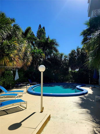 Outdoor area with a swimming pool surrounded by lush greenery and lounge chairs.